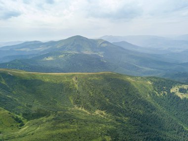 Bulutlu havada Ukrayna Karpatlarının yüksek dağları. Hava aracı görünümü.