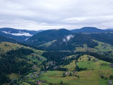 Yazın Ukrayna Karpat Dağları 'nın yeşil yamaçlarında. Bulutlu bir sabah, alçak bulutlar. Hava aracı görünümü.