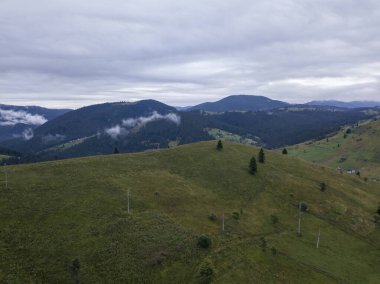 Yazın Ukrayna Karpat Dağları 'nın yeşil yamaçlarında. Bulutlu bir sabah, alçak bulutlar. Hava aracı görünümü.