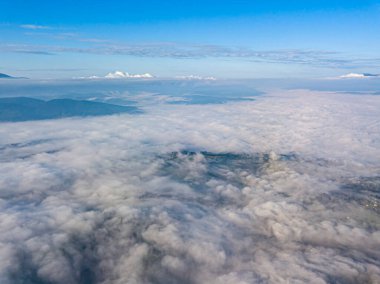Dağlardaki bulutların üstünde yüksek bir uçuş. Hava aracı görünümü.