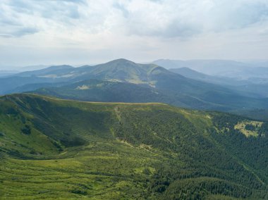 Bulutlu havada Ukrayna Karpatlarının yüksek dağları. Hava aracı görünümü.