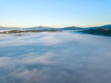 Ukrayna Karpatları 'nda yaz aylarında sislerin üzerinden uçarlar. Ufuktaki dağlar. Yoğun bir sis tabakası daimi bir halıyla dağları kaplar. Hava aracı görünümü.