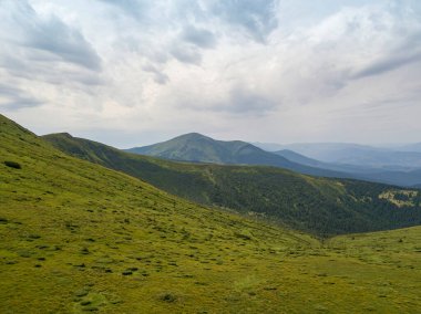 Bulutlu havada Ukrayna Karpatlarının yüksek dağları. Hava aracı görünümü.