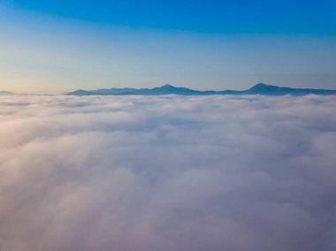 Ukrayna Karpatları 'nda yaz aylarında sislerin üzerinden uçarlar. Ufuktaki dağlar. Hava aracı görünümü.