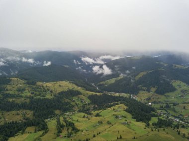 Yazın Ukrayna Karpat Dağları 'nın yeşil yamaçlarında. Bulutlu bir sabah, alçak bulutlar. Hava aracı görünümü.