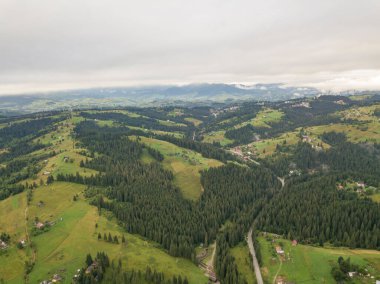 Yazın Ukrayna Karpat Dağları 'nın yeşil yamaçlarında. Bulutlu bir sabah, alçak bulutlar. Hava aracı görünümü.