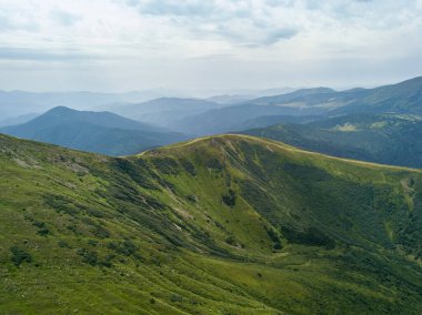 Bulutlu havada Ukrayna Karpatlarının yüksek dağları. Hava aracı görünümü.