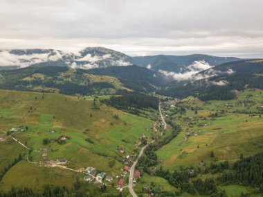 Yazın Ukrayna Karpat Dağları 'nın yeşil yamaçlarında. Bulutlu bir sabah, alçak bulutlar. Hava aracı görünümü.