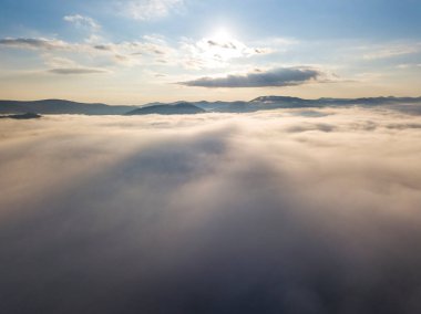 Ukrayna Karpatları 'nda yaz aylarında sislerin üzerinden uçarlar. Ufuktaki dağlar. Yoğun bir sis tabakası daimi bir halıyla dağları kaplar. Hava aracı görünümü.
