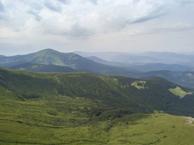 Bulutlu havada Ukrayna Karpatlarının yüksek dağları. Hava aracı görünümü.