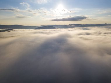 Ukrayna Karpatları 'nda yaz aylarında sislerin üzerinden uçarlar. Ufuktaki dağlar. Yoğun bir sis tabakası daimi bir halıyla dağları kaplar. Hava aracı görünümü.