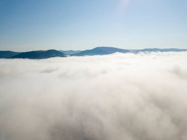 Ukrayna Karpatları 'nda yaz aylarında sislerin üzerinden uçarlar. Ufuktaki dağlar. Yoğun bir sis tabakası daimi bir halıyla dağları kaplar. Hava aracı görünümü.