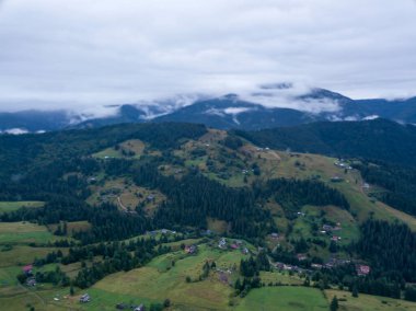Yazın Ukrayna Karpat Dağları 'nın yeşil yamaçlarında. Bulutlu bir sabah, alçak bulutlar. Hava aracı görünümü.