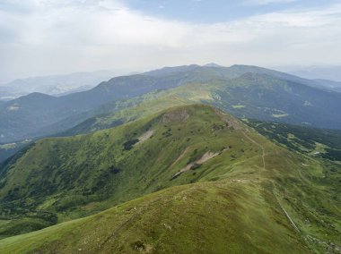 Bulutlu havada Ukrayna Karpatlarının yüksek dağları. Hava aracı görünümü.