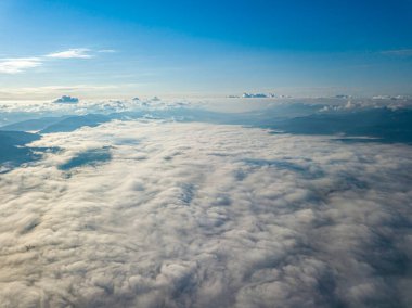 Dağlardaki bulutların üstünde yüksek bir uçuş. Hava aracı görünümü.