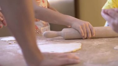 Annesi ve kardeşleriyle pizza hamuru yoğuran bir kız. Seçici odak