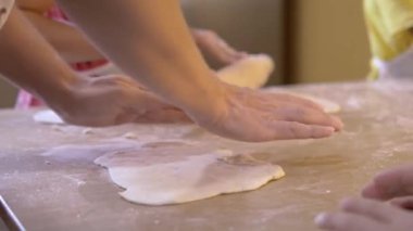 Çocuklara yemek pişirmeyi öğretmek için hamur hazırlayan kadın. Aile yemekleri kavramı. Seçici odak.
