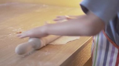 Önlüklü bir çocuk masaya raptiye takmış pizza hamuru yoğuruyor. Seçici odak