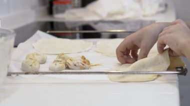 Çocuğun elleri pizza hamurunu dolu hamur torbalarının yanındaki fırın tepsisine koyuyor. Seçici odak