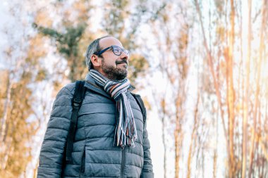 Ormanda gökyüzüne bakan gülümseyen adam. Doğada rahatlama kavramı.