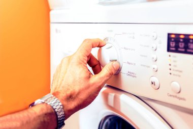 Man's hand turning the washing machine wheel