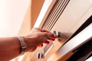 Man's hand using oven controls for food preparation
