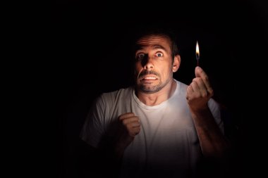 Karanlıkta elinde kibritle kameraya bakan korkmuş bir adam. Bilinç kaybı konsepti. Seçici odak.