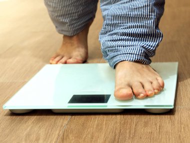 Male leg stepping on weigh scales. Healthy lifestyle, food and sport concept. Selective focus