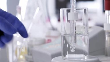 Close-up of scientist's hands measuring ph. Selective focus.