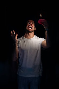 Kızgın adam karanlıkta kibritle yukarı bakıyor. Bilinç kaybı kavramı. Seçici odak.