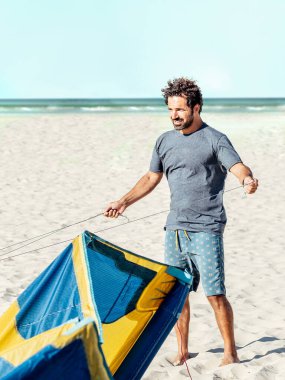 Kumsalda uçurtma halatları hazırlayan adam. Erkekler uçurtma halatlarını çözer.