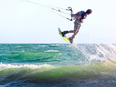 Genç uçurtma sörfçüsü gün batımında denize atlar. Seçici odak.