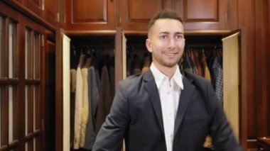 Genç adam soyunma odasında ceket giyiyor.