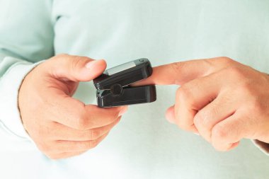 Evde nabız oksimetresiyle kan oksijeni seviyesini ölçen biri var. Sağlık denetimi kavramı