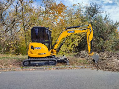 Modern sarı JCB kazıcı veya kazıcı açık havada kazı yapıyor