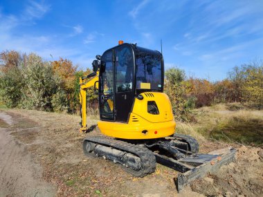 Modern sarı JCB mini kazıcı veya kazıcı açık havada kazı çalışması yapıyor