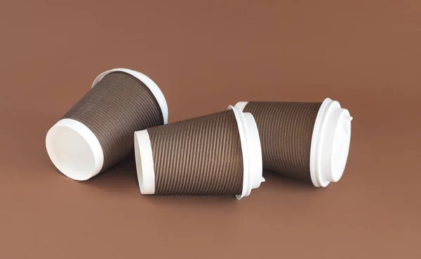 コピースペース付き茶色の背景にキャップ付き3枚の紙段ボールコーヒーカップ — ストック写真