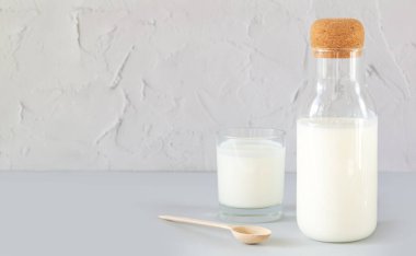 Ev yapımı yoğurt mantarı, kefir, mayalanmış süt ya da ekşi krema ile mutfak masasında cam ve ahşap kaşık içilen eski bir kavanoz.