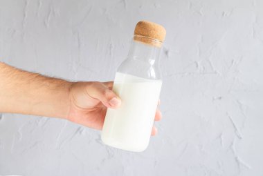 Elinde bir şişe ev yapımı yoğurt, kefir, tereyağı ya da doğal mayalanmış süt tutan adam.