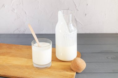 Ev yapımı yoğurt mantarı, kefir, mayalanmış süt ya da ekşi krema ile mutfak masasında cam ve ahşap kaşık içilen eski bir kavanoz.