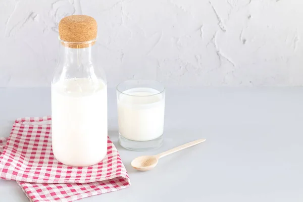 Ev yapımı yoğurt mantarı, kefir, mayalanmış süt ya da ekşi krema ile mutfak masasında cam ve ahşap kaşık içilen eski bir kavanoz.