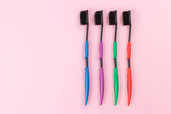 Pembe Arka Plan Manzaralı Siyah Tüylü Renkli Plastik Diş Fırçaları — Stok fotoğraf