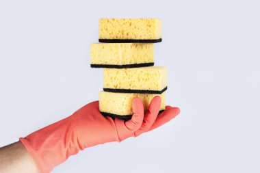 Turuncu kauçuk eldiven içinde temizlik için sarı süngerler.