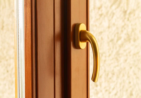 Metal window handle in golden color close-up
