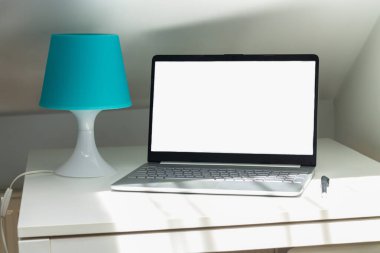 Office workspace with open laptop computer or notebook with blank white screen on desktop. Remote work or education concept