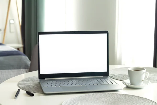 Open laptop computer with blank white monitor screen mockup. Home office desk table workspace concept