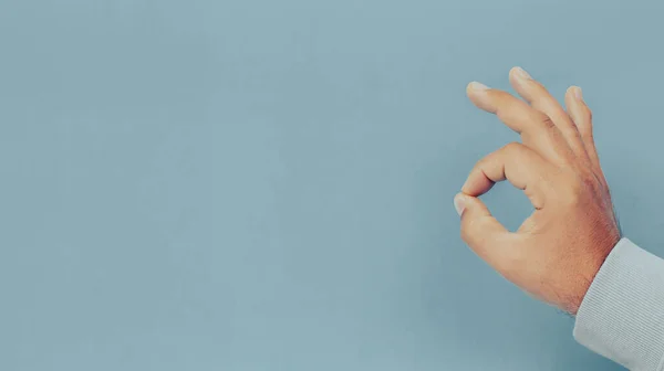 Male hand with OK sign or gesture on blue background