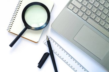 Laptop, not defteri, kalem, cetvel ve büyüteçle iş geçmişi. Ofis malzemeleri. Üst görünüm