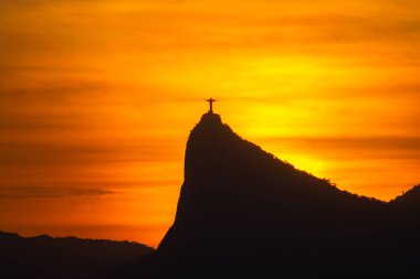 Rio de Janeiro, Brezilya - CIRCA 2021: Cristo Redentor Panoraması (Kurtarıcı İsa) turuncu gökyüzü ile günbatımında