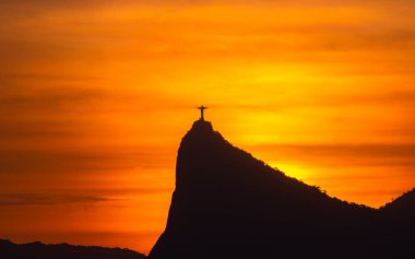 Rio de Janeiro, Brezilya - CIRCA 2021: Cristo Redentor Panoraması (Kurtarıcı İsa) turuncu gökyüzü ile günbatımında